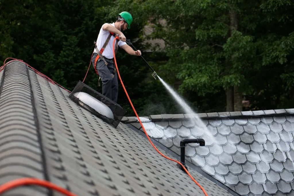 man spraying Roof Maxx's treatment on the roof